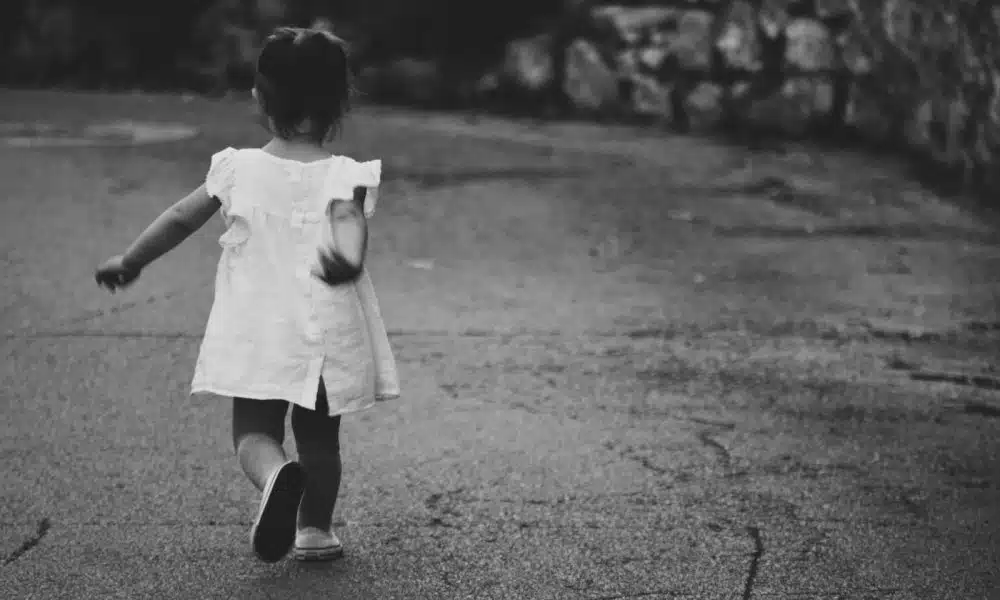 gray scale photography of girl walking towards destination