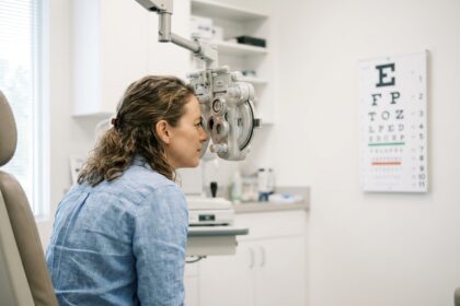Femme de 38 ans lors d'un bilan de vue chez l'opticien, lisant un tableau optométrique avec attention